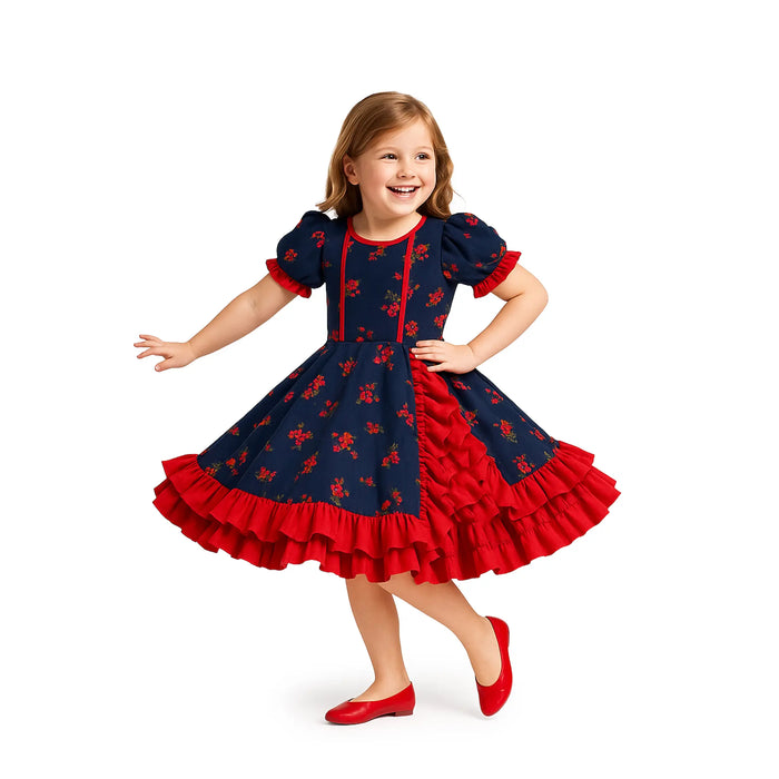 Chica joven con vestido azul marino con motivos florales rojos y volantes sobre fondo blanco