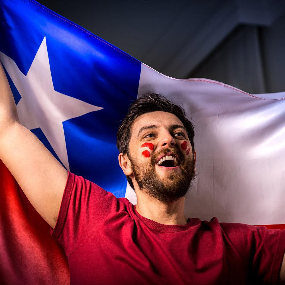 Un hombre con gafas de sol que lleva una camiseta negra con una bandera chilena.