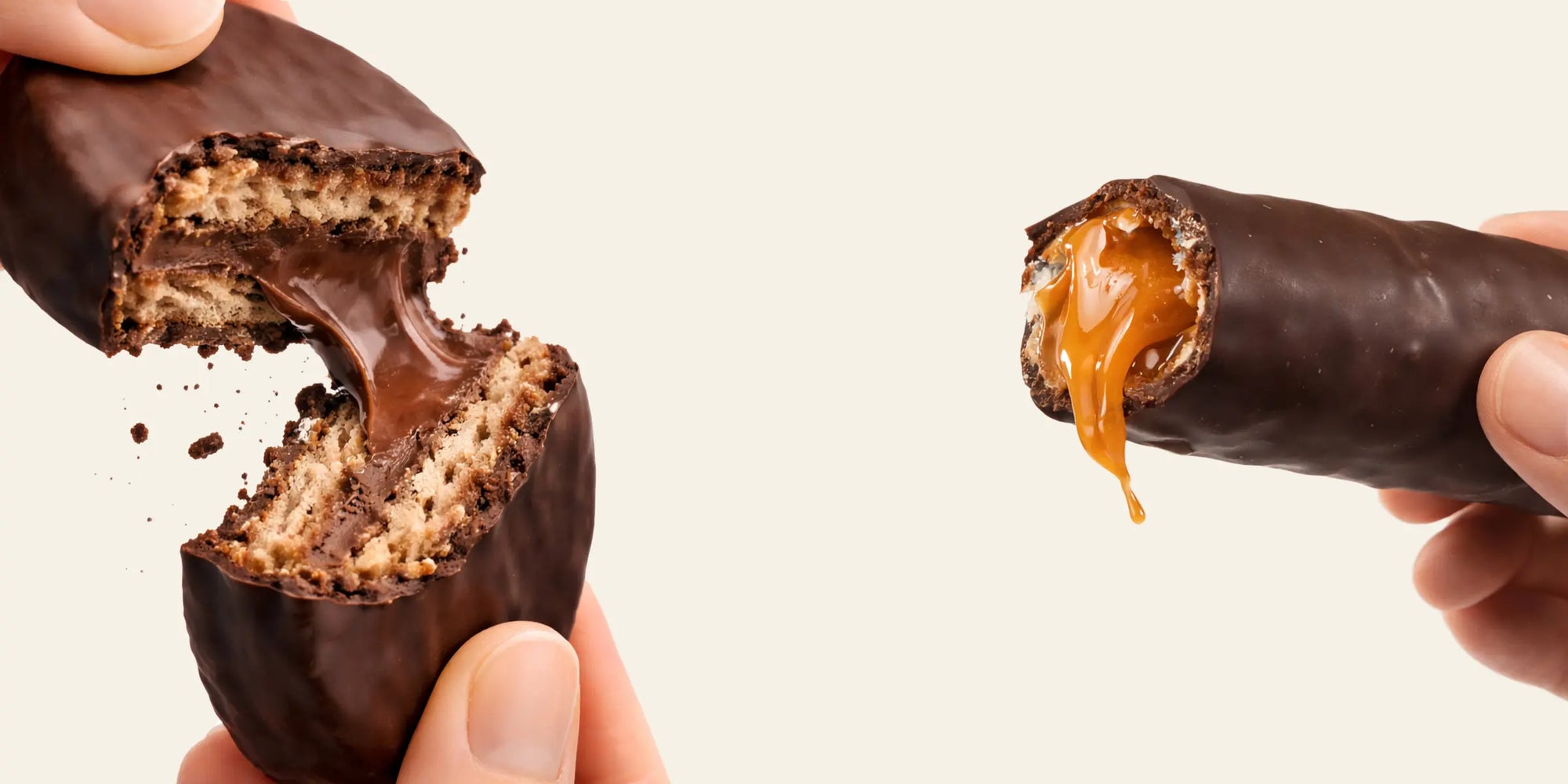 Galleta cubierta de chocolate con un mordisco, que muestra la textura interior, sostenida por una mano sobre un fondo neutro.